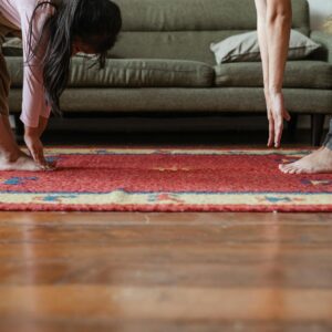 crop barefoot ethnic mother and daughter doing stretching exercises together