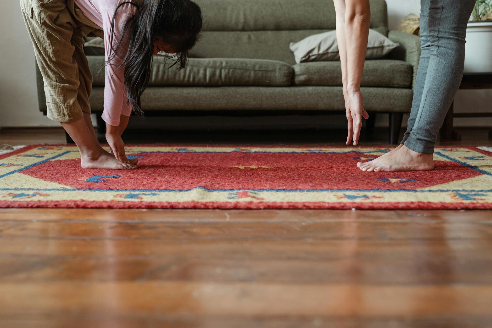 crop barefoot ethnic mother and daughter doing stretching exercises together