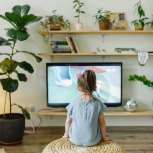 faceless girl watching tv on wicker stool at home