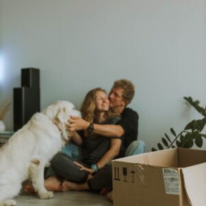 a couple sitting on the floor while playing with their dog